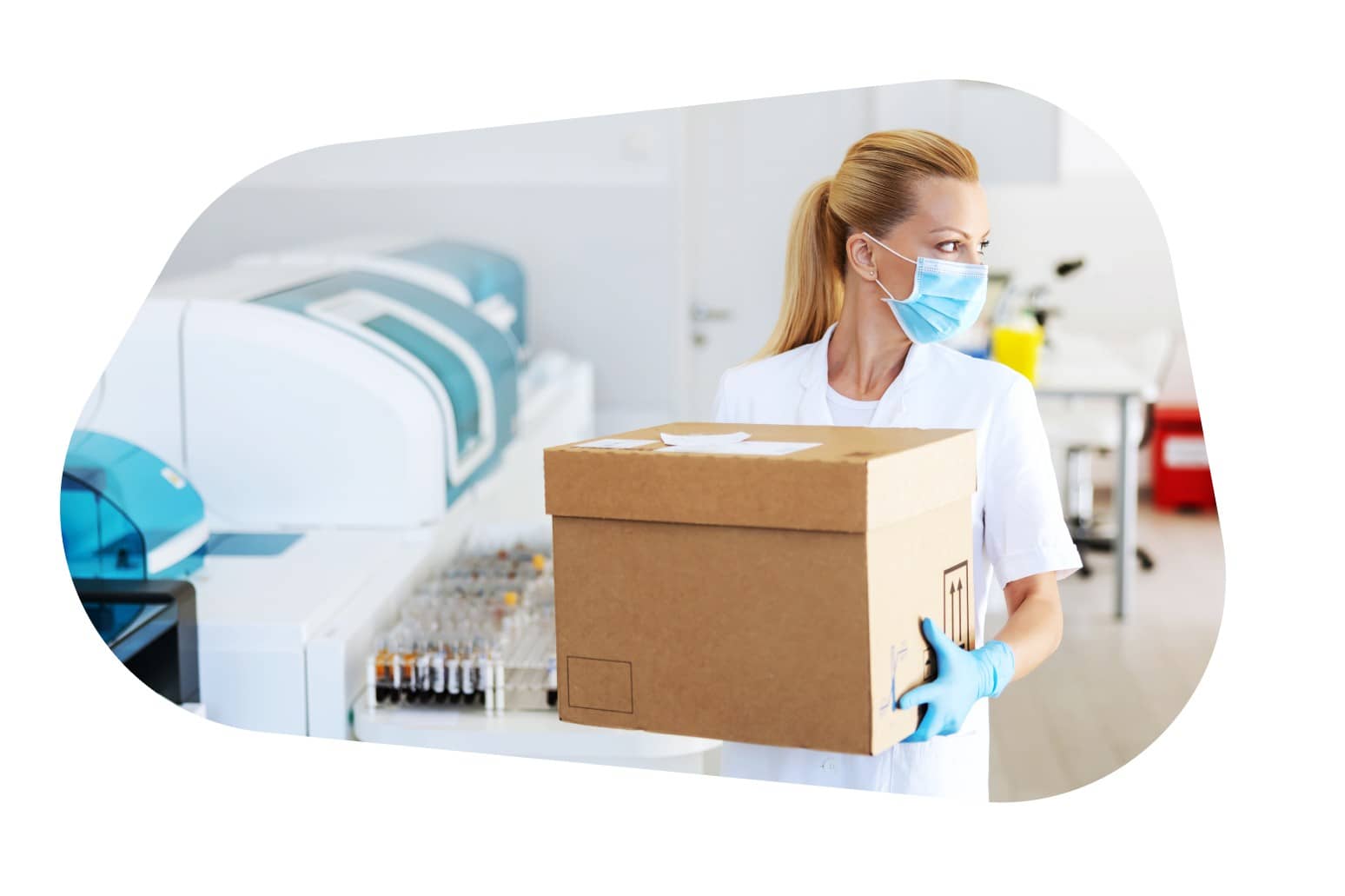 A healthcare professional wearing a mask and gloves, carrying a large cardboard box in a laboratory setting.